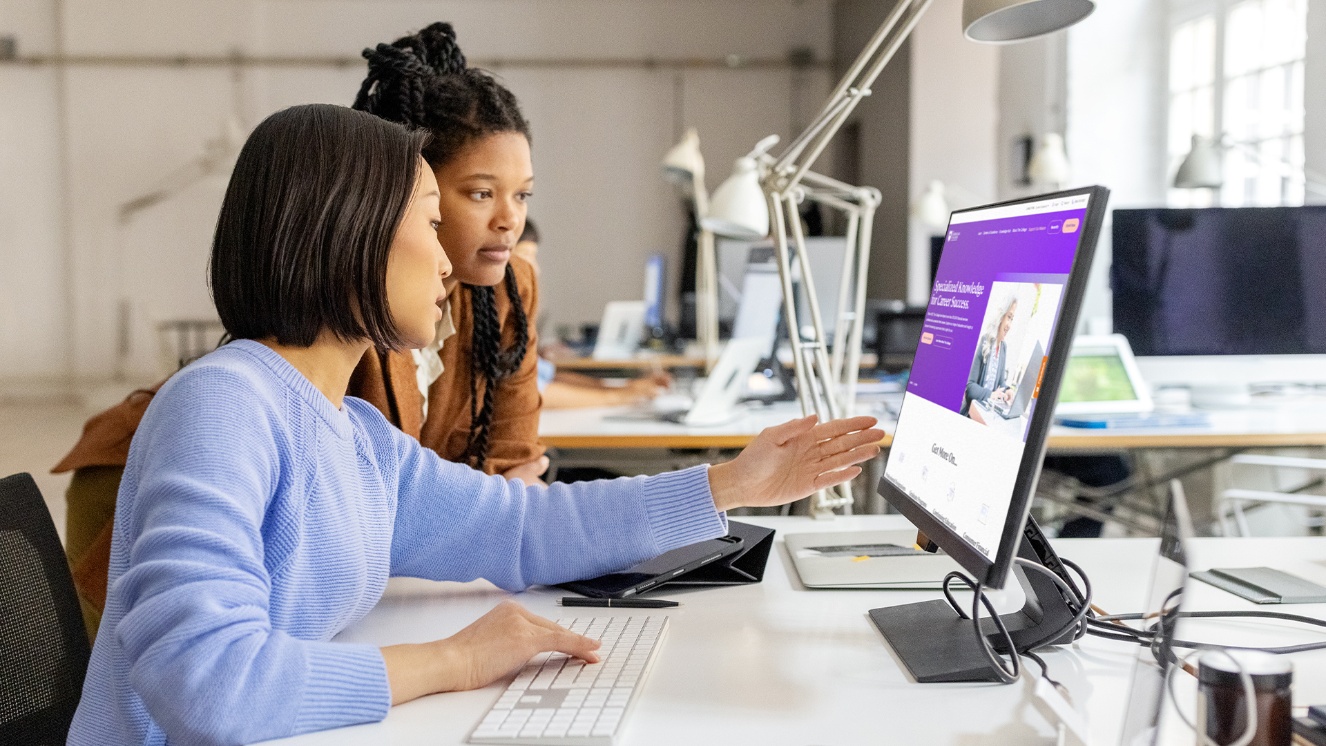 Two female coworkers looking at a computer together