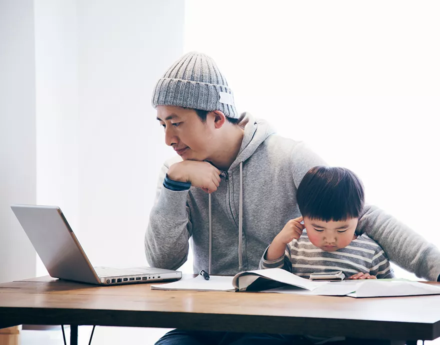 Man working at a laptop with his child