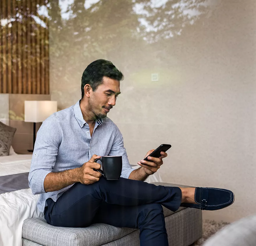 A man sitting on a bed and looking at his phone