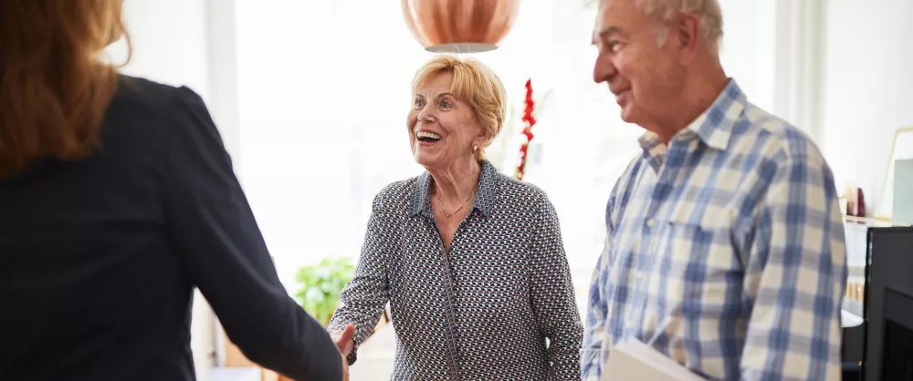 A couple shaking hands with a woman