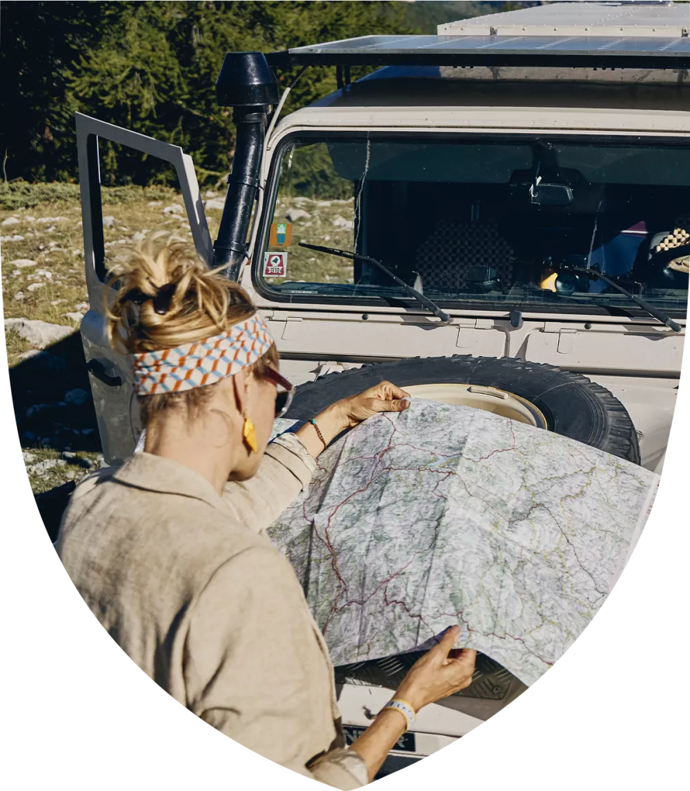 Woman looking at a map on the hood of her car