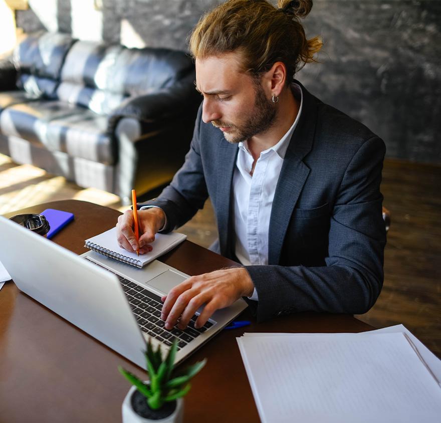 Male young professional on his laptop taking notes