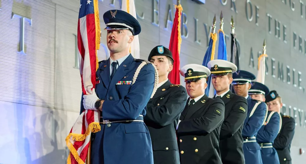 Military servicemen standing in a line holding the flag